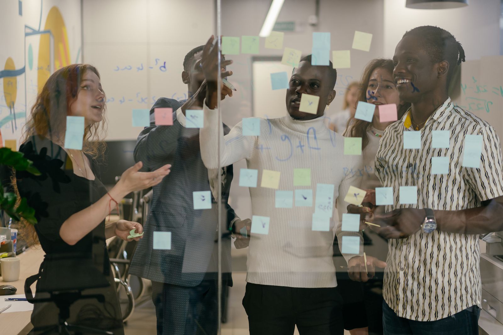 Colleagues clustered around a glass wall covered in sticky notes during an offsite workshop session