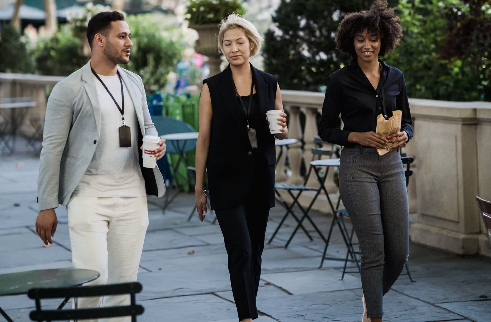 Colleagues walking outside with coffee and lanyards during a break in an offsite