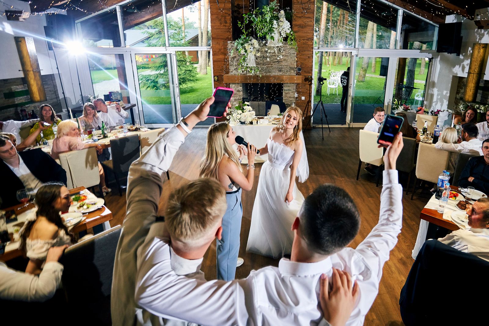 Wedding guests raising their phones to capture the bride during the reception